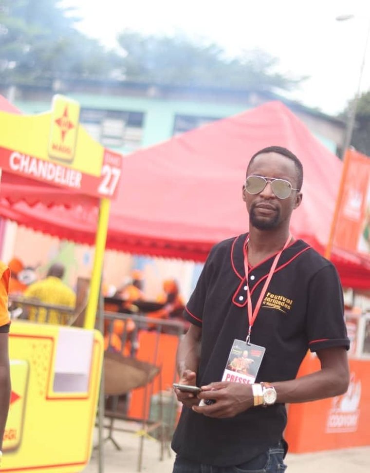Mac Arthur sur le terrain du Festival des Grillades d'Abidjan, badge presse au cou